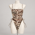 Resort No Pressure One Piece Swimsuit Tiger (No Promo) on an ivory display mannequin; AI-generated styling visualization. Original product photos retained for reference.